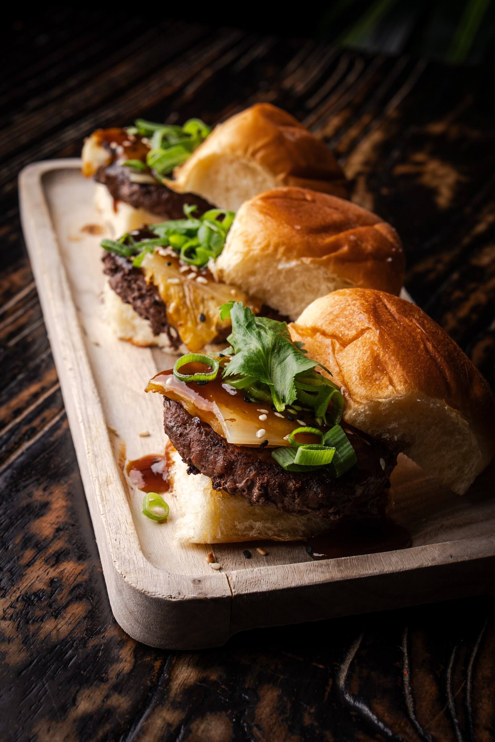 Three teriyaki-glazed sliders with Swiss, grilled pineapple and scallions on Hawaiian sweet rolls.